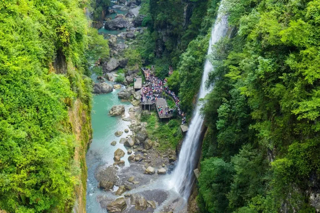 zhangjiajie in summer waterfall valley with visitors and green forest after rain