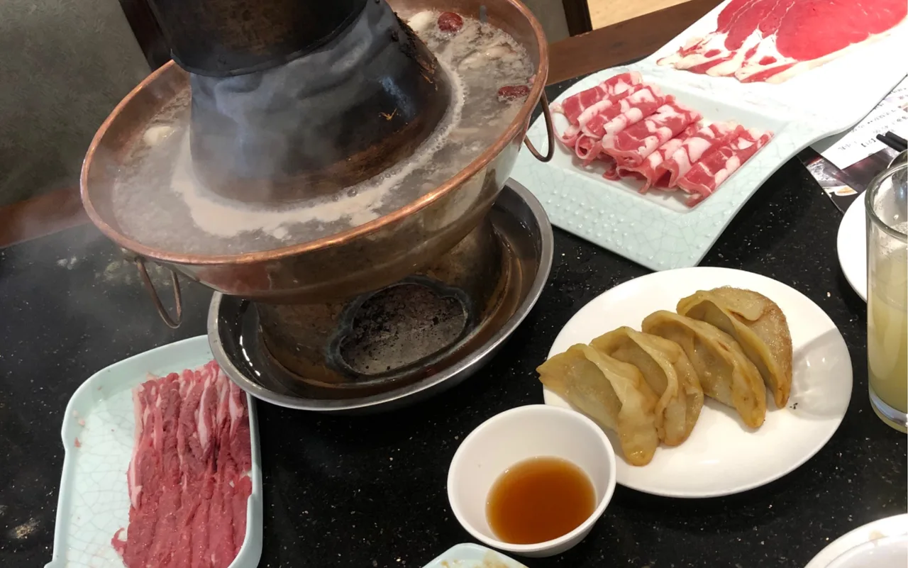 Halal mutton hotpot in a charcoal copper pot with hand-sliced lamb in Shanghai