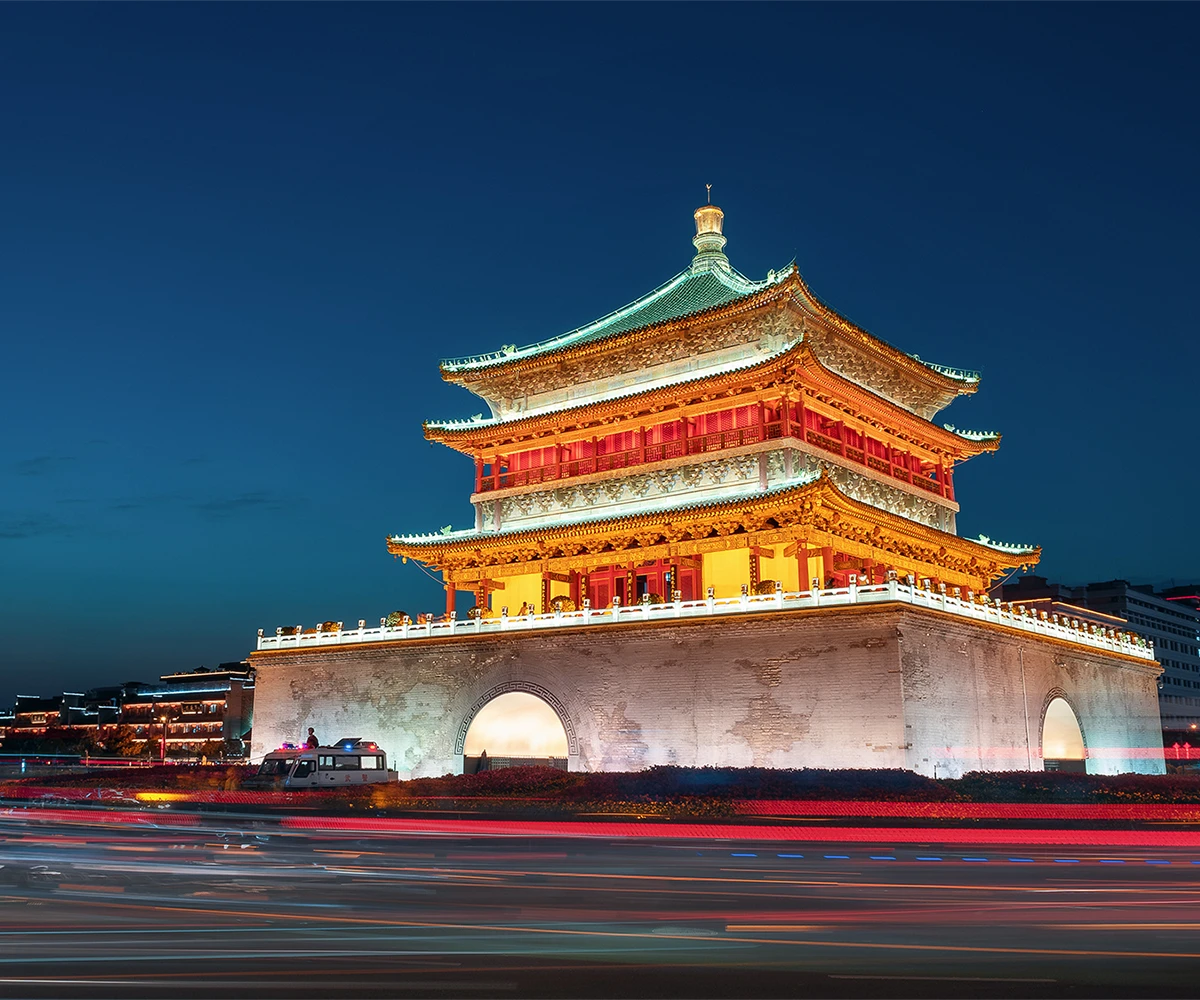 Xi'an Bell Tower illuminated at night with traffic light trails