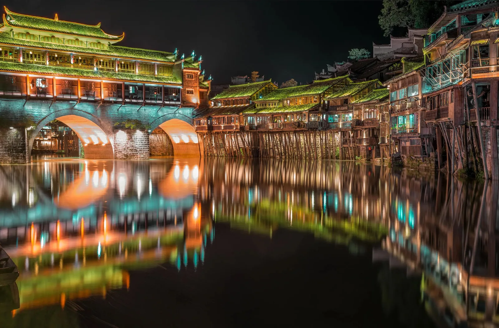 Hong Bridge and stilted houses reflected in the Tuo River at night in Fenghuang Ancient Town