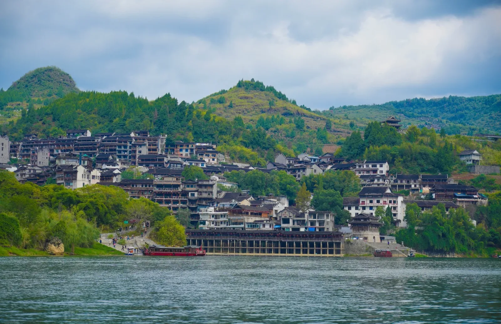 Furong Ancient Town seen from river level with sightseeing boats at the pier