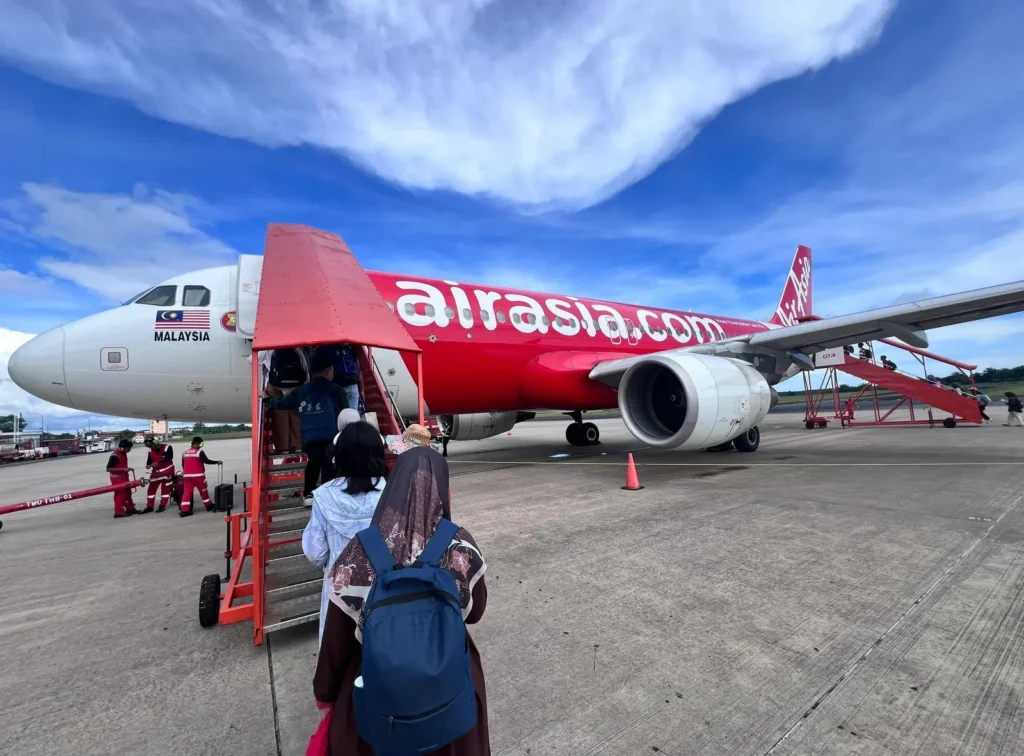 Malaysian travelers boarding a Malaysia-flagged AirAsia plane on the tarmac