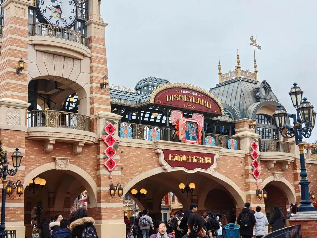Entrance gate of Shanghai Disneyland with the park clock tower and visitors
