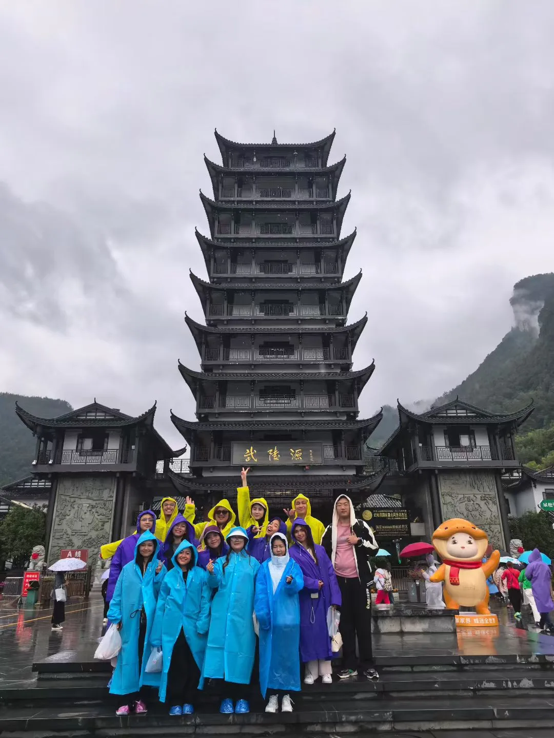 Tour group in rain ponchos at the Wulingyuan entrance gate tower of Zhangjiajie National Forest Park