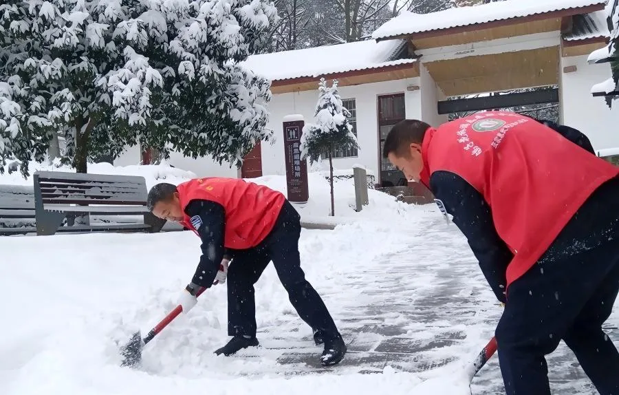 Scenic area staff clearing fresh snow from a walkway during winter snowfall