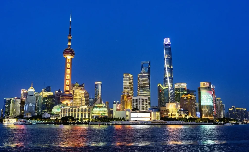 Lujiazui skyline across the Huangpu River at dusk, with the Oriental Pearl Tower and Shanghai Tower lit up
