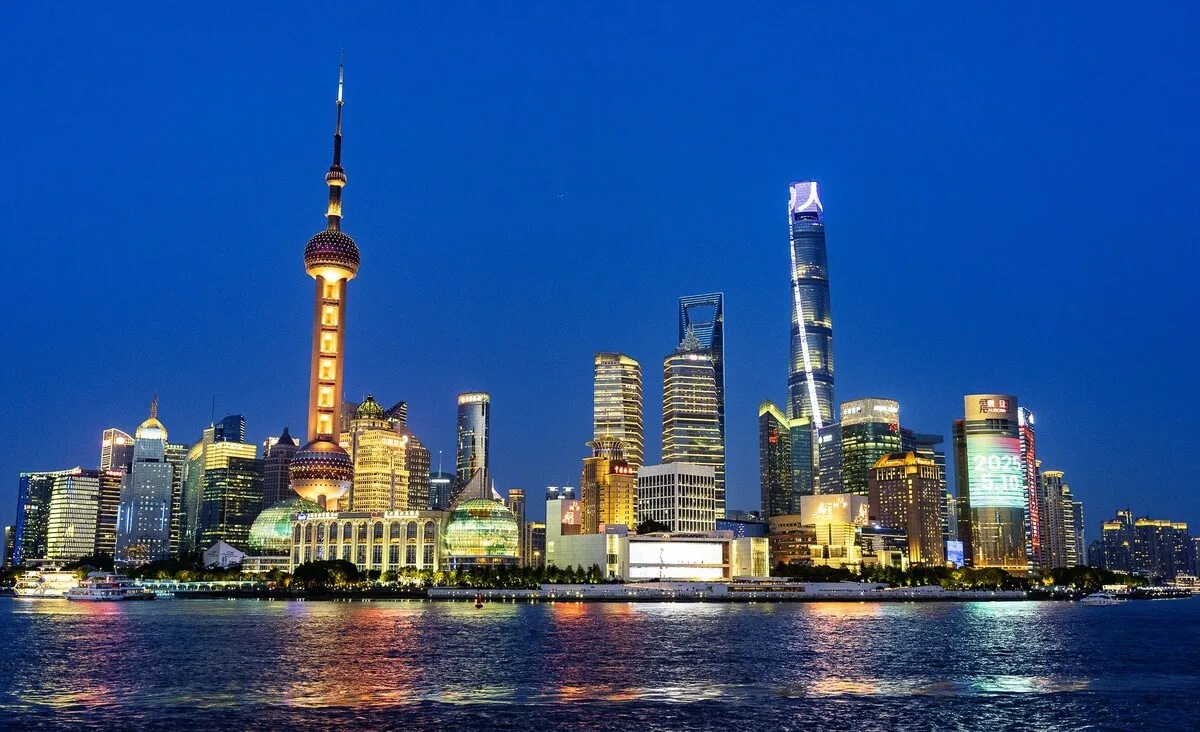 Lujiazui skyline across the Huangpu River at dusk, with the Oriental Pearl Tower and Shanghai Tower lit up