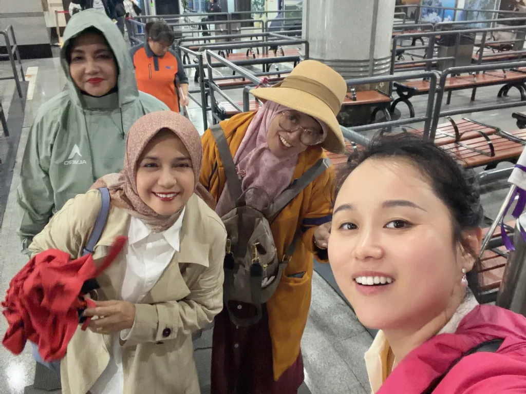 Female tour guide taking a selfie with smiling Muslim women travelers in hijab at a station in China