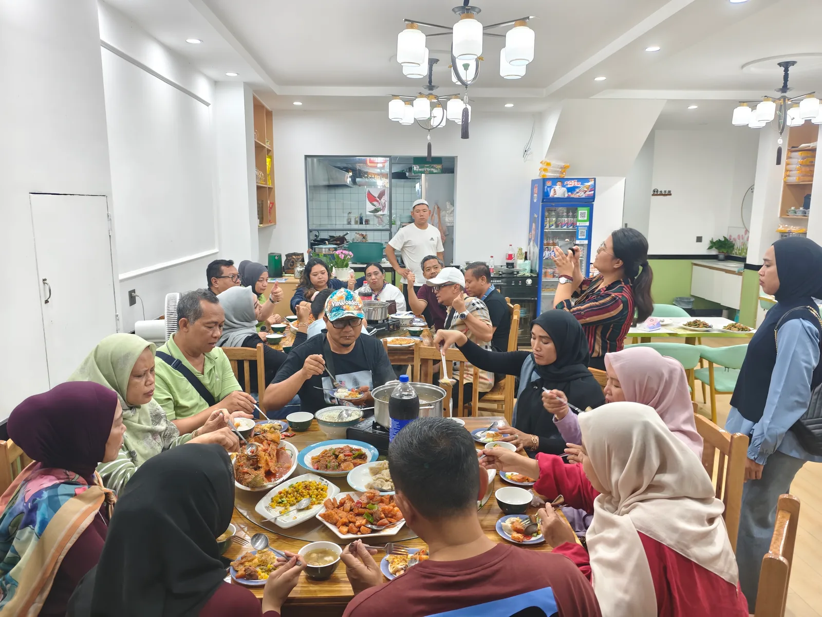 A larger Muslim tour group having a halal group dinner across two round tables at a halal restaurant in China