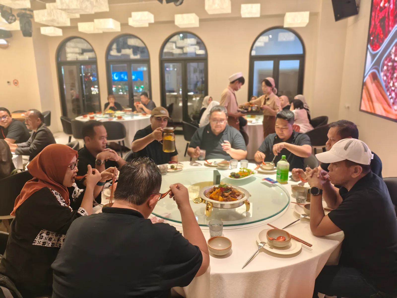 A group of Muslim travelers sharing a set dinner around a lazy-susan table at a halal restaurant in China