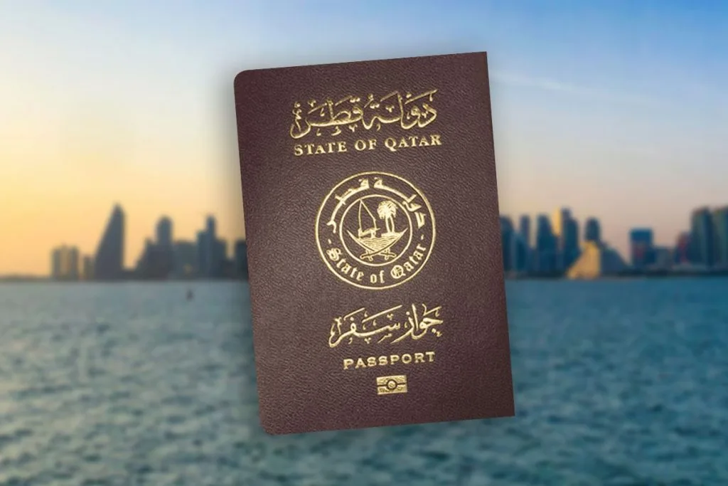 Qatari passport cover with the State of Qatar emblem, held up against a blurred waterfront city skyline
